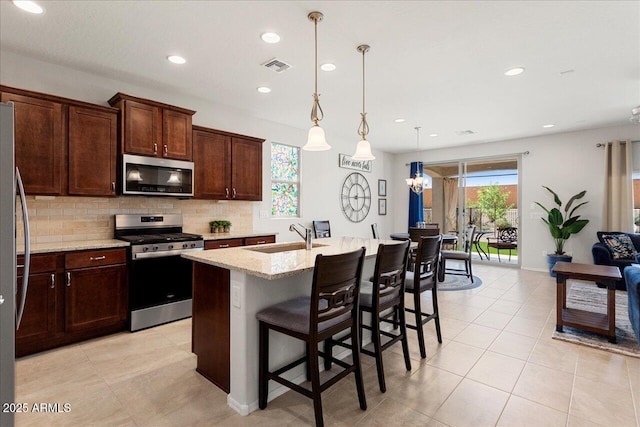 26947 W Adam Ave, Buckeye, AZ 85396 - kitchen with stainless steel appliances, a sink, backsplash, light stone counters, and light tile patterned floors