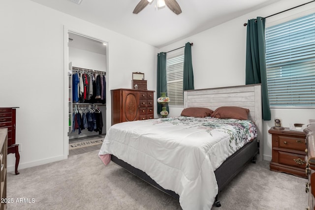 bedroom with ceiling fan, a closet, light colored carpet, and a spacious closet