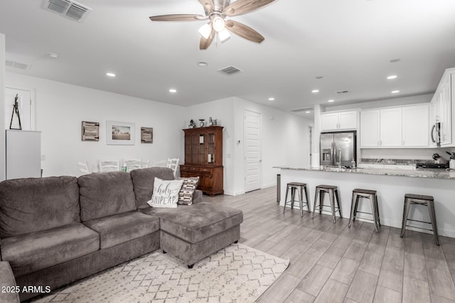 living room featuring ceiling fan and light wood-type flooring