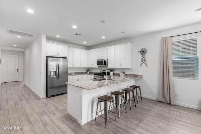 kitchen featuring white cabinets, appliances with stainless steel finishes, kitchen peninsula, and sink