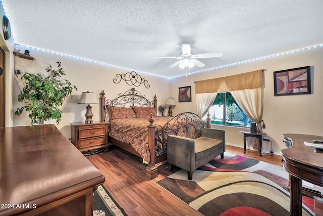 bedroom with ceiling fan, wood-type flooring, and a textured ceiling