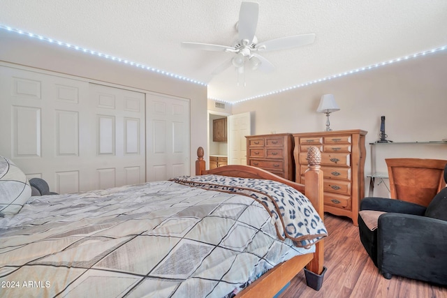 bedroom with ceiling fan, wood-type flooring, a textured ceiling, and a closet