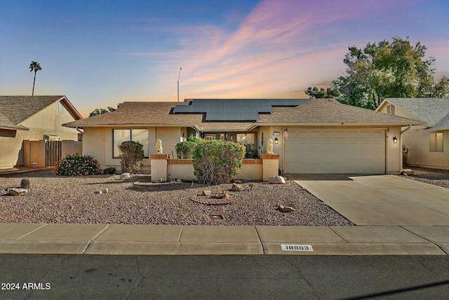 ranch-style home featuring solar panels and a garage