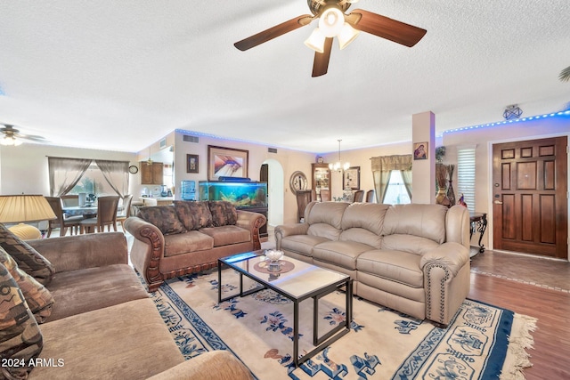 living room with ceiling fan with notable chandelier, light hardwood / wood-style floors, and a textured ceiling