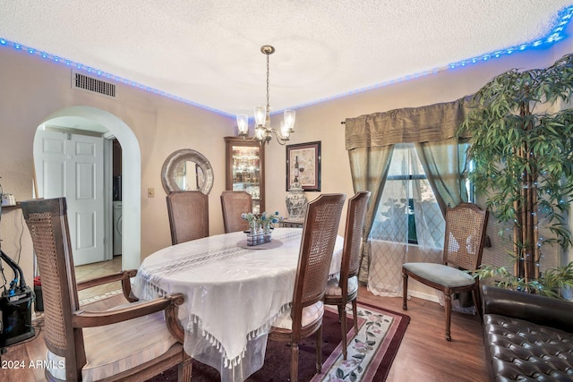 dining space with a chandelier, wood-type flooring, and a textured ceiling