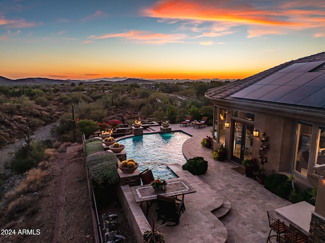 pool at dusk featuring a patio area and a mountain view