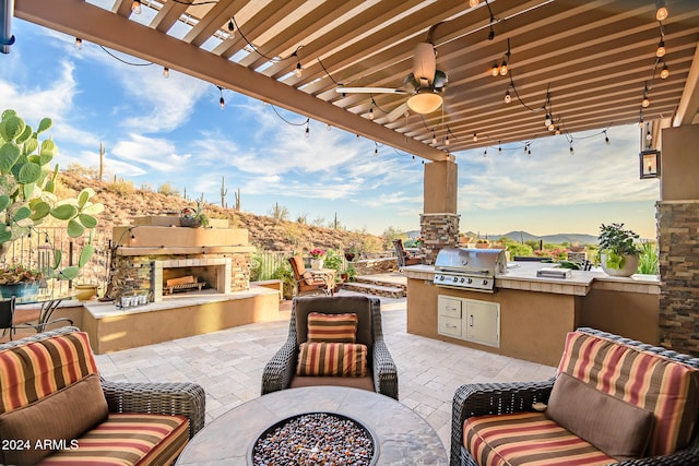 view of patio / terrace featuring area for grilling, an outdoor stone fireplace, an outdoor fire pit, exterior kitchen, and ceiling fan