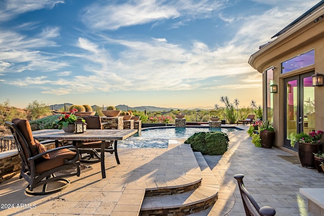 patio terrace at dusk with a mountain view and pool water feature