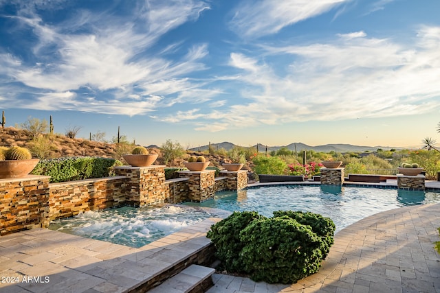 view of swimming pool with a hot tub, a mountain view, and pool water feature