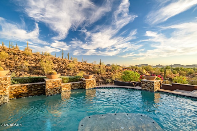 view of pool featuring a mountain view, pool water feature, and a jacuzzi