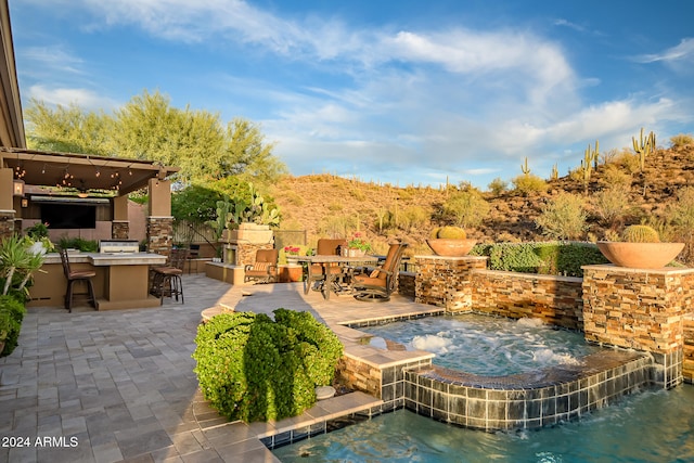 view of swimming pool featuring area for grilling, an in ground hot tub, exterior bar, pool water feature, and a patio area