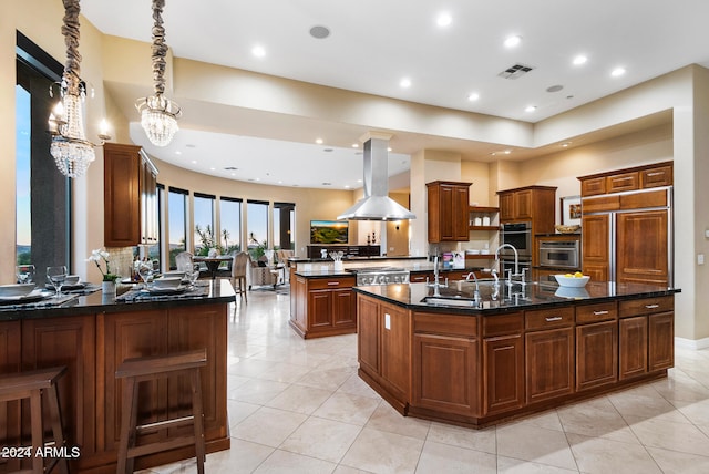 kitchen with a center island with sink, island range hood, a notable chandelier, and kitchen peninsula