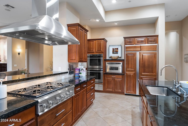 kitchen featuring extractor fan, dark stone counters, sink, light tile patterned flooring, and appliances with stainless steel finishes