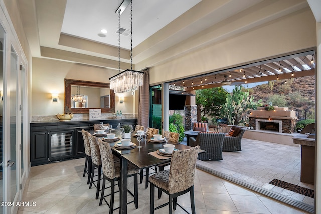 dining space featuring beverage cooler, a raised ceiling, and light tile patterned floors