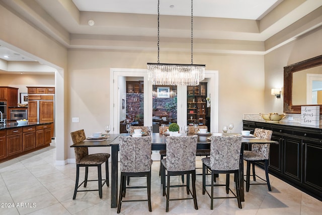 tiled dining area with an inviting chandelier and a raised ceiling