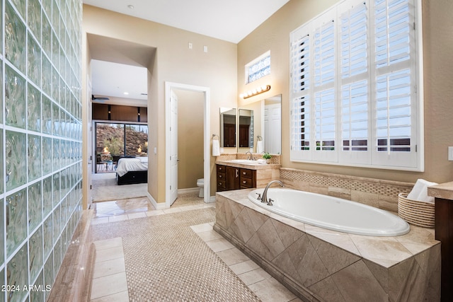 bathroom with vanity, toilet, a healthy amount of sunlight, and a relaxing tiled tub