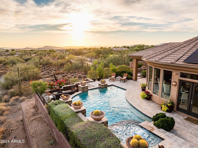 pool at dusk featuring a patio area and pool water feature