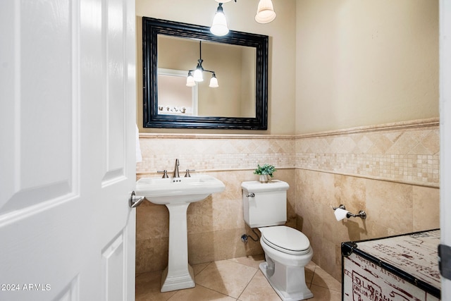 bathroom featuring toilet, tile patterned floors, tile walls, and sink