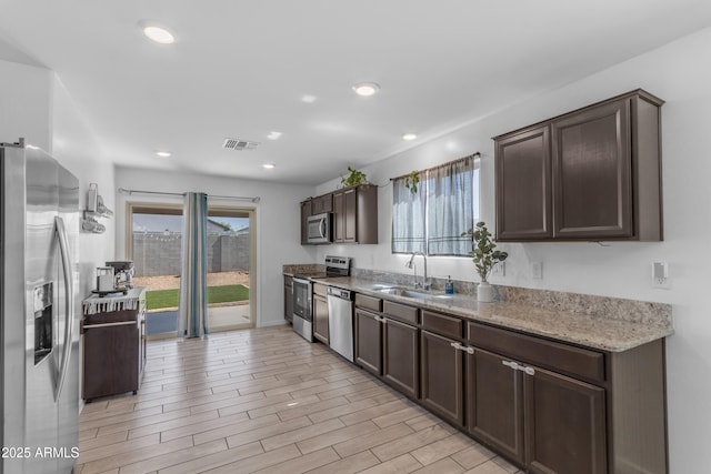 9442 E Silo Rd, Florence, AZ 85132 - kitchen with appliances with stainless steel finishes, dark brown cabinets, a sink, recessed lighting, and light stone counters