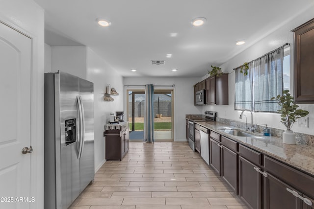9442 E Silo Rd, Florence, AZ 85132 - kitchen with stainless steel appliances, a sink, dark brown cabinetry, light stone counters, and recessed lighting