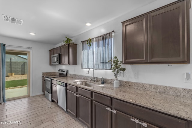 9442 E Silo Rd, Florence, AZ 85132 - kitchen with a sink, appliances with stainless steel finishes, dark brown cabinets, light stone counters, and recessed lighting