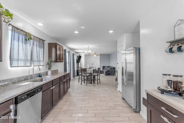 9442 E Silo Rd, Florence, AZ 85132 - kitchen with appliances with stainless steel finishes, a sink, dark brown cabinets, open floor plan, and light wood-style flooring
