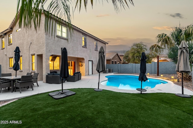 pool at dusk with an outdoor hangout area, a patio, a yard, and a fenced backyard