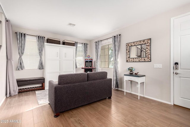 living room featuring light wood finished floors, visible vents, and baseboards