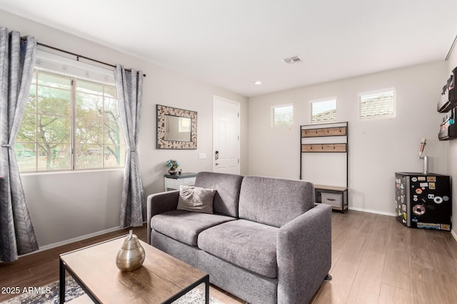 living area featuring recessed lighting, visible vents, baseboards, and wood finished floors