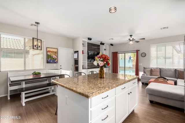 kitchen featuring dark wood-type flooring, a kitchen island, visible vents, white cabinets, and open floor plan