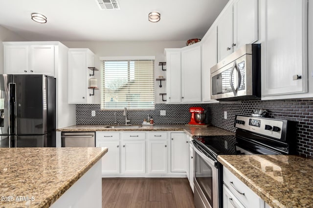 kitchen with stainless steel appliances, tasteful backsplash, visible vents, white cabinets, and a sink