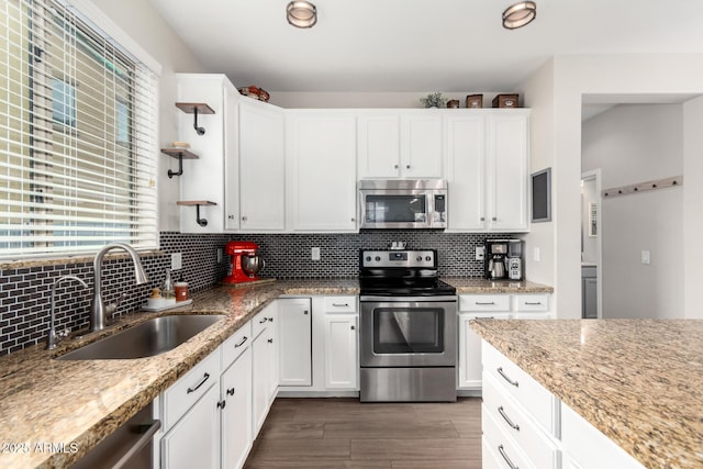 kitchen with white cabinetry, decorative backsplash, stainless steel appliances, and a sink