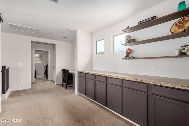 hallway with attic access, a wealth of natural light, light colored carpet, and baseboards