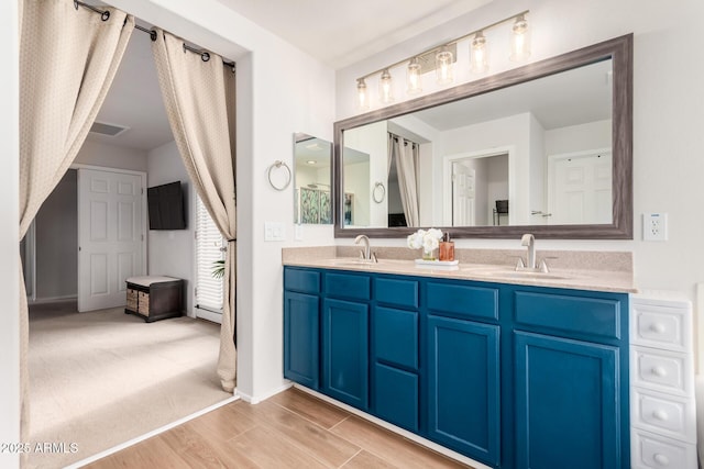 bathroom featuring double vanity, wood finished floors, a sink, and visible vents