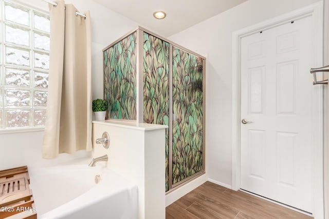 bathroom with recessed lighting, plenty of natural light, a bath, and wood finished floors