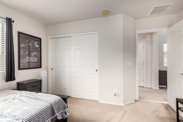 bedroom with baseboards, visible vents, a closet, and light colored carpet