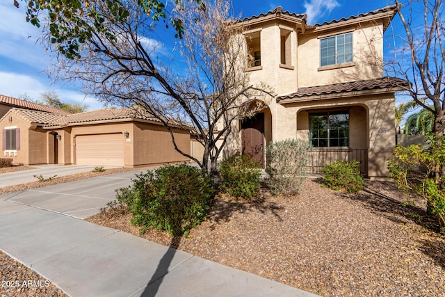 mediterranean / spanish-style house featuring driveway, an attached garage, a tiled roof, and stucco siding