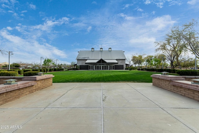 back of property featuring metal roof, a lawn, and a patio