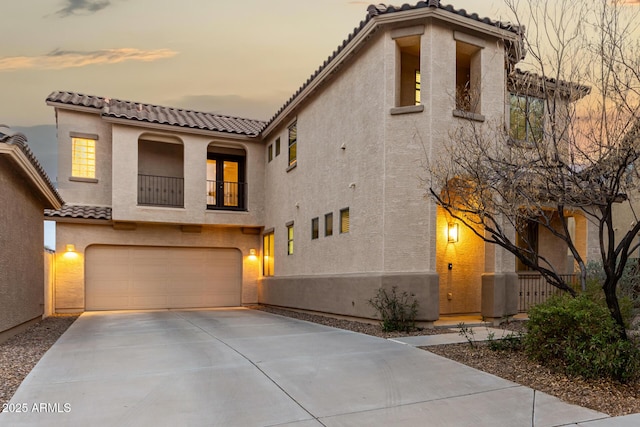 mediterranean / spanish home with driveway, a garage, a balcony, a tile roof, and stucco siding