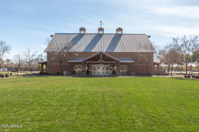 back of property with metal roof, a lawn, and a standing seam roof