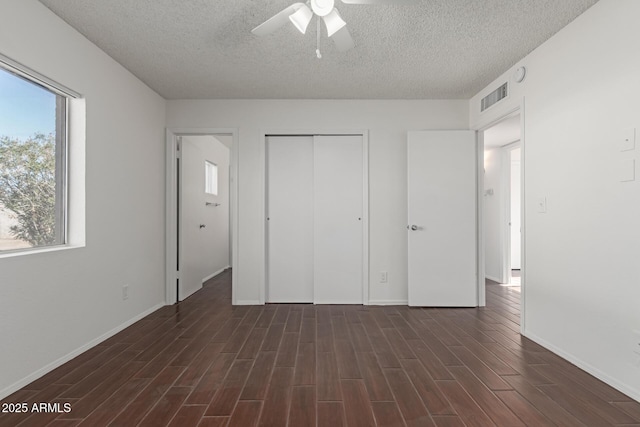 unfurnished bedroom featuring multiple windows, ceiling fan, a closet, and a textured ceiling