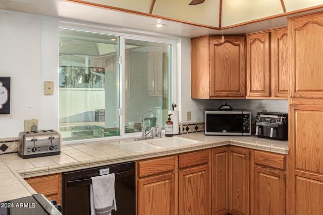 kitchen featuring black dishwasher, sink, and tile counters