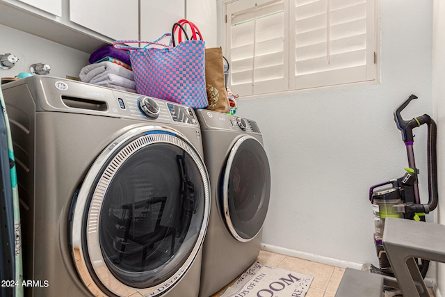 washroom with cabinets, light tile patterned flooring, and washer and clothes dryer