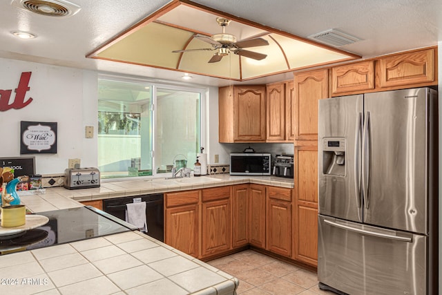 kitchen with ceiling fan, light tile patterned floors, a textured ceiling, stainless steel appliances, and tile counters