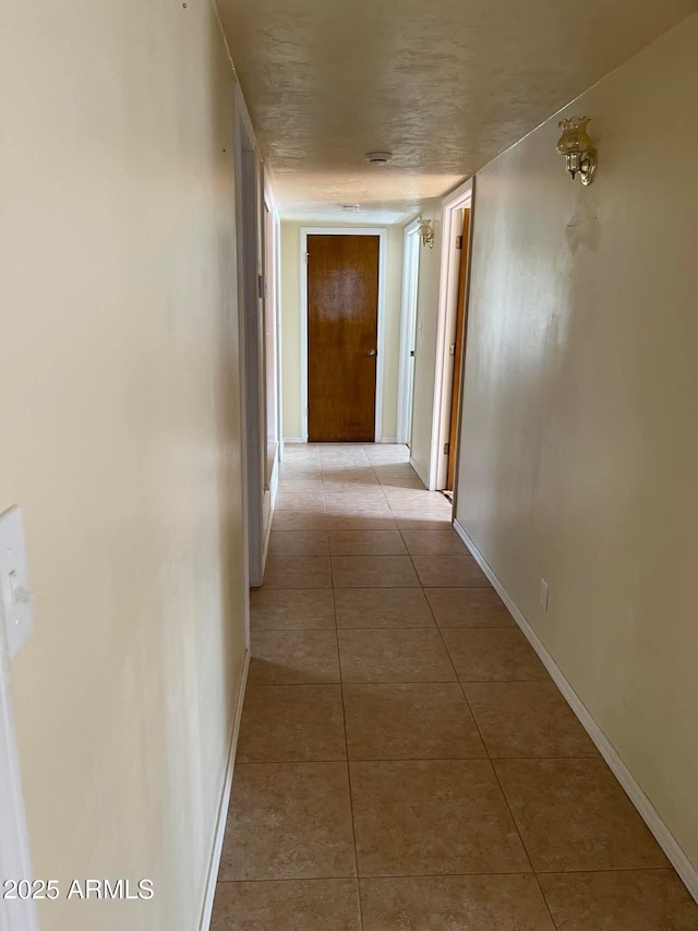 hallway featuring tile patterned flooring and baseboards