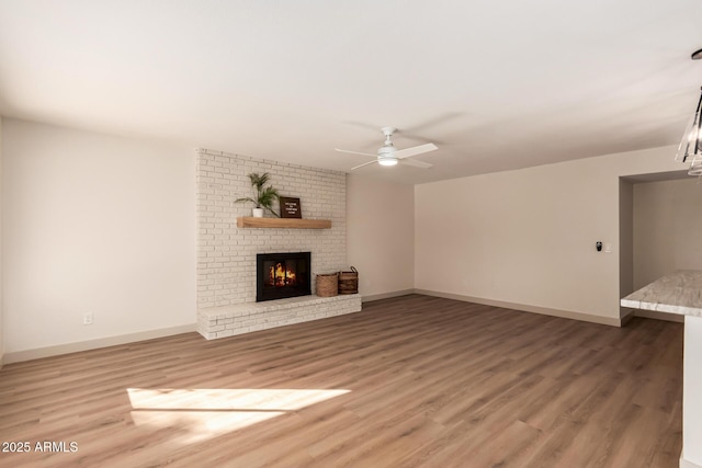 unfurnished living room with a brick fireplace, ceiling fan, and hardwood / wood-style flooring