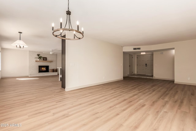 unfurnished living room featuring light hardwood / wood-style floors, a chandelier, and a fireplace