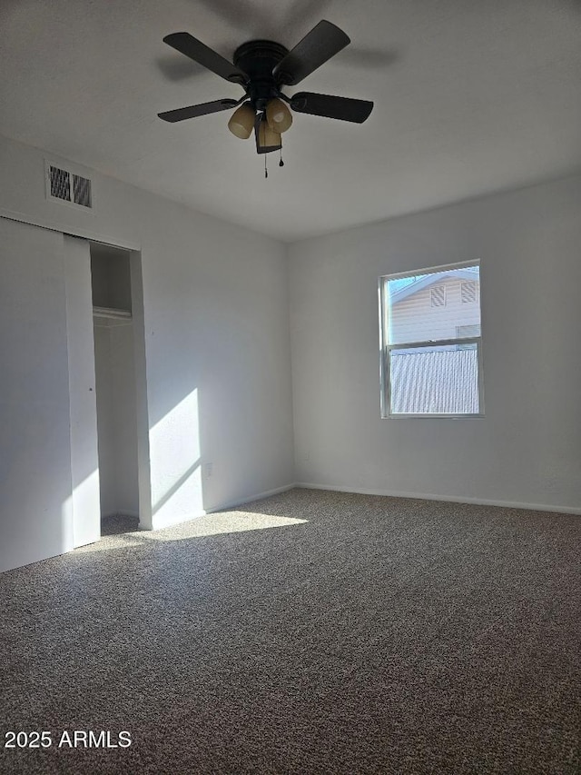 carpeted spare room featuring visible vents and ceiling fan