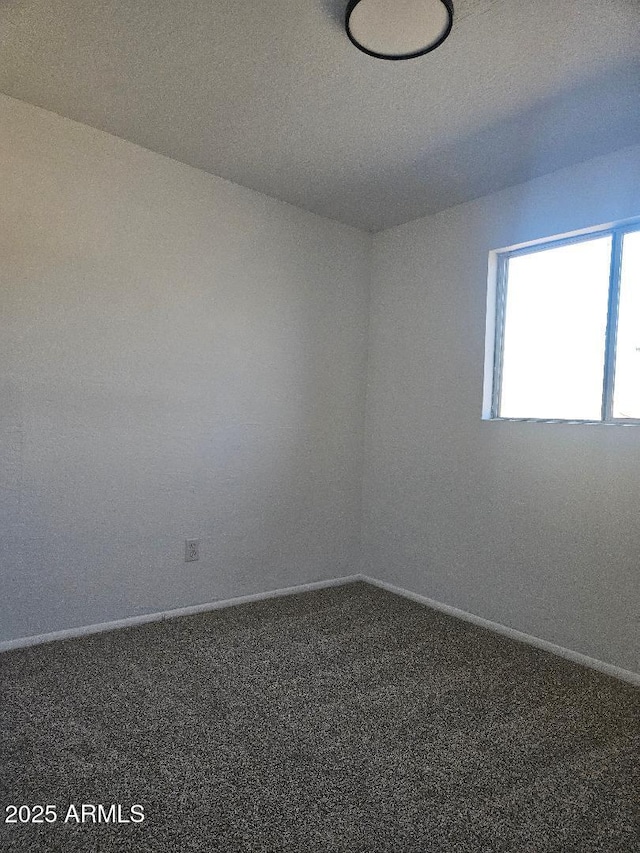 empty room featuring carpet and baseboards