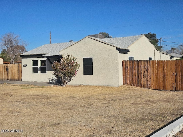 view of side of property featuring fence and stucco siding